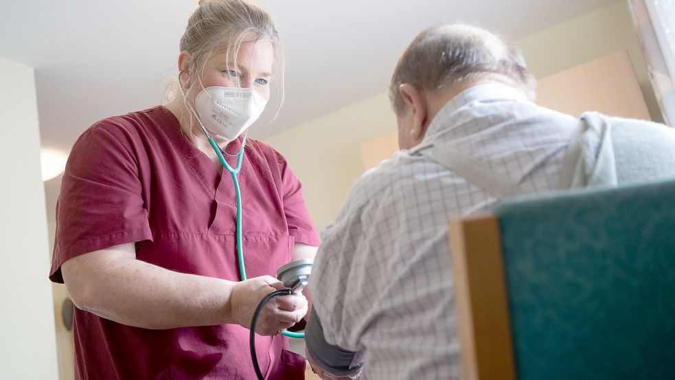 Eine Pflegekraft misst bei einem Bewohner Blutdruck. Sie trägt eine Maske - so wird es auch in Oberledinger Einrichtungen gehandhabt. Foto: Marijan Murat/dpa