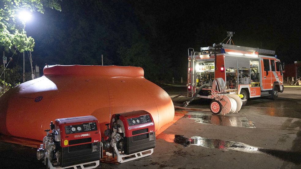 Die Feuerwehr füllt Löschwasser in eine sogenannte Blase (links) und leitet sie von dort mit Pumpen zum Brand. Foto: Christian Ender/dpa