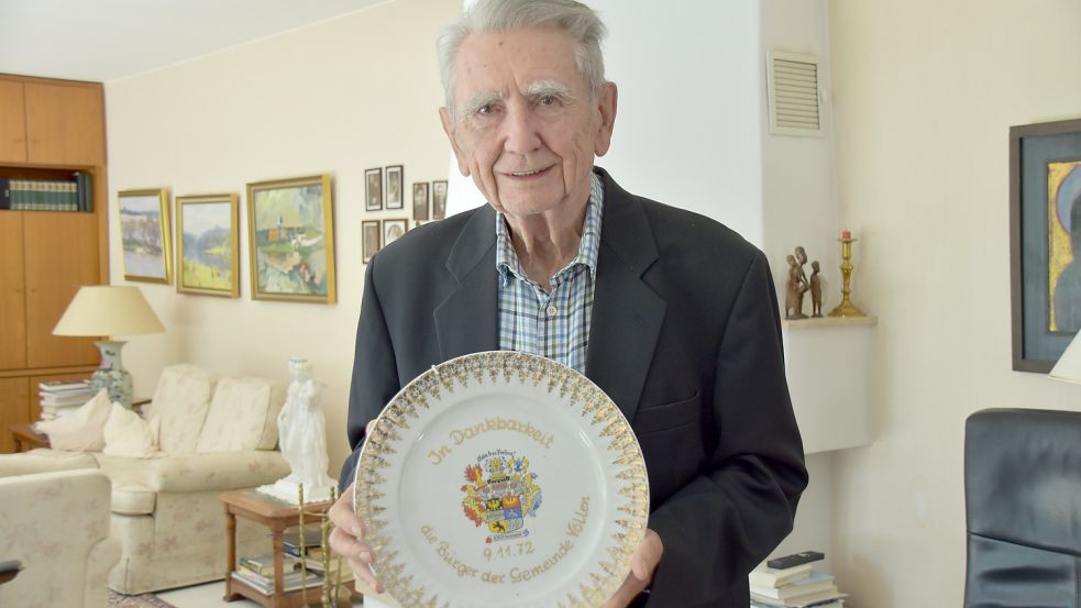 Horst Milde im Wohnzimmer seines Oldenburger Zuhauses. In den Händen hält er einen Wandteller, den er als Dankeschön von Völlenern erhalten hat. Foto: Wehry