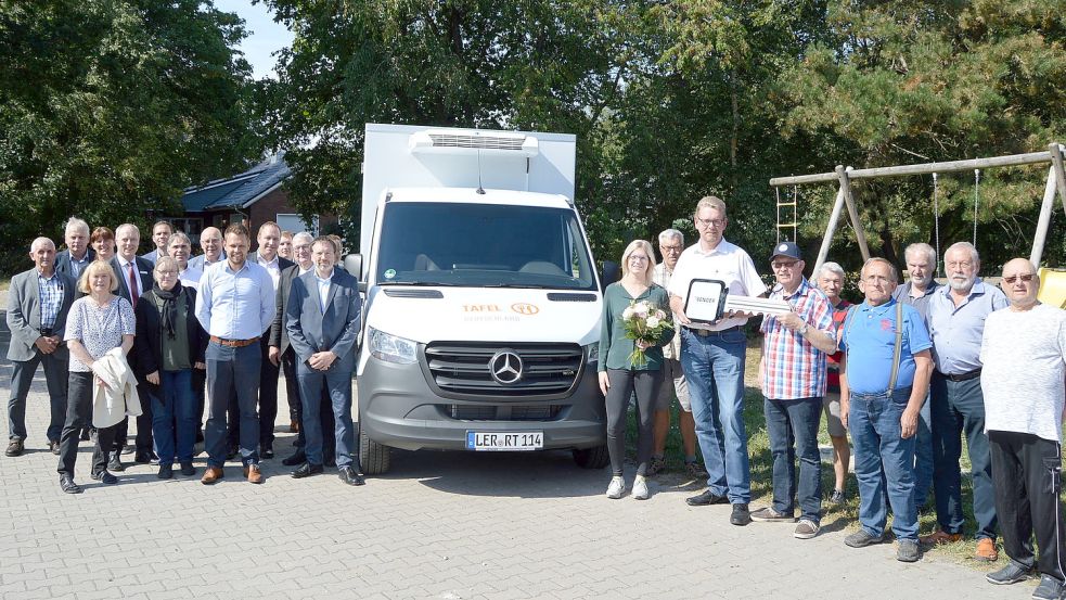 Symbolische Schlüsselübergabe für das neue Kühlfahrzeug durch Meik Schrapper (mit Schlüssel), Mitarbeiter der Firma Auto Senger GmbH aus Friesoythe (Mercedes-Benz), an den Leiter der Tafel Rhauderfehn, Egon Plaisier (kariertes Hemd mit Kappe). Links sind die Vertreter der Spender (Kirchen, Banken, Gemeinden) und rechts die Fahrer der Tafel Rhauderfehn zu sehen. Foto: Weers
