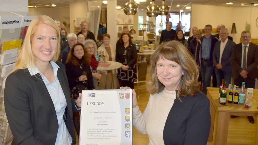 Kerstin Kontny (links), Leiterin Abteilung Tourismus, Handel und Dienstleistungen bei der Industrie- und Handelskammer für Ostfriesland und Papenburg, überreichte Ursula Schröder, Inhaberin des Unternehmens Möbel Schröder, anlässlich des 100-jährigen Bestehens der Firma eine Urkunde. Foto: Ammermann