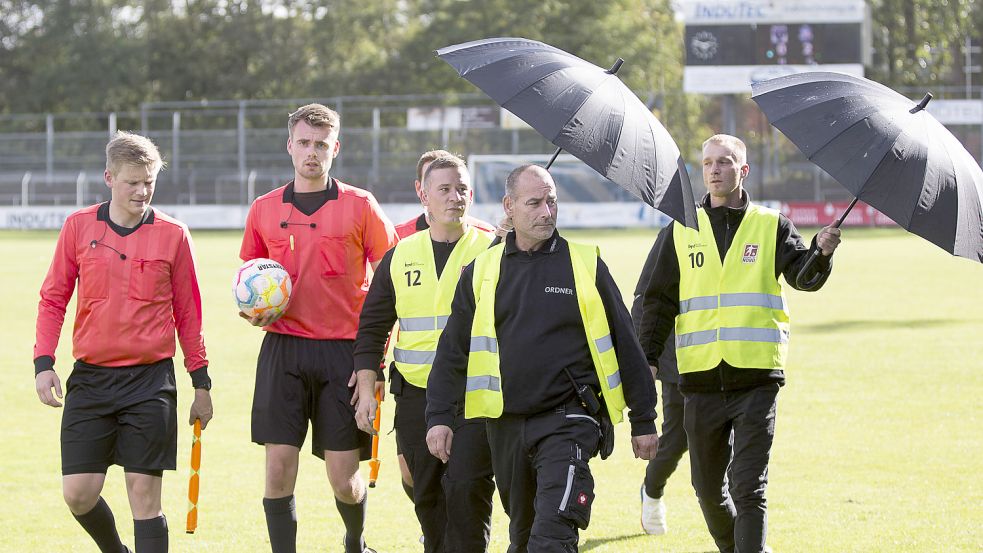 Der Schiedsrichter wurde beim Gang in die Kabine in der Halbzeit und nach dem Spiel vor dem Emder Fanblock von Ordnern mit Regenschirmen geschützt. Foto: Doden/Emden