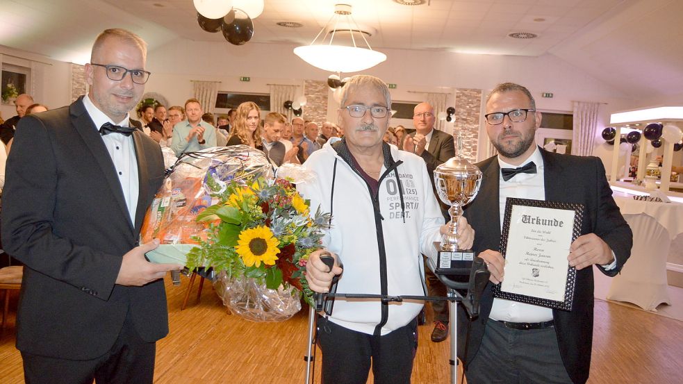 Sven Dieken (2. Vorsitzender des VfL Viktoria Flachsmeer, links) und Andre Hessenius (Vereinsvorsitzender, rechts) zeichneten Heinrich „Heiner“ Jansen als „Viktorianer des Jahres“ mit einem Pokal, einer Urkunde und einem Präsentkorb aus. Fotos: Weers