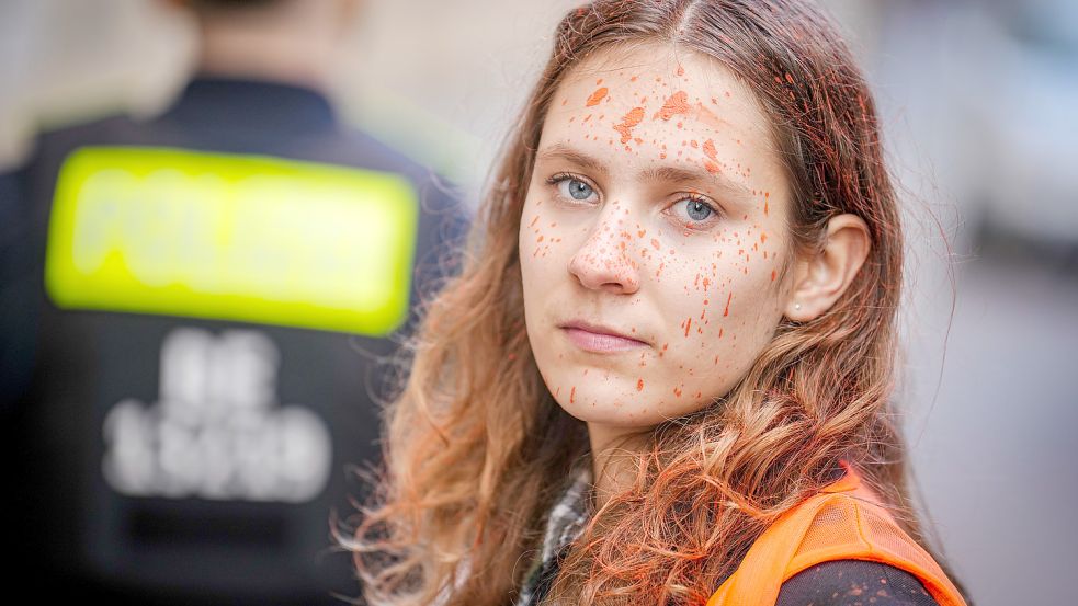 Lina Schinköthe, Klimaaktivistin der Organisation „Die letzte Generation“ steht vor der Parteizentrale der FDP zwischen Polizeibeamten. Zuvor wurde die Parteizentrale mit Farbe besprüht. Foto: dpa/Kay Nietfeld