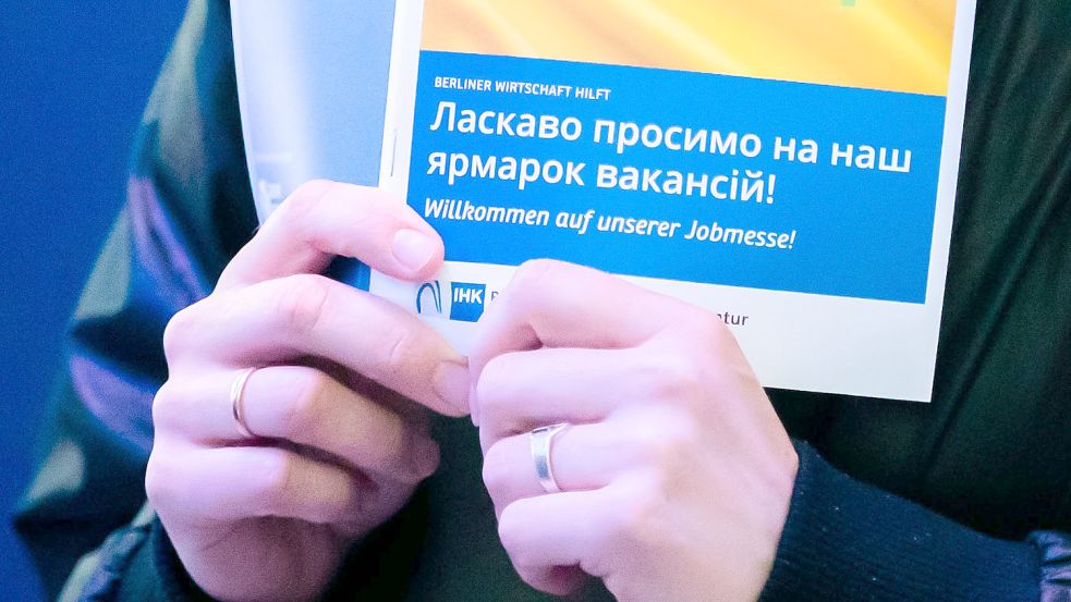 Eine Frau hält bei einer Jobmesse für ukrainische Geflüchtete von der IHK Berlin und der Agentur für Arbeit den Messeplan in der Hand. Foto: Soeder/dpa