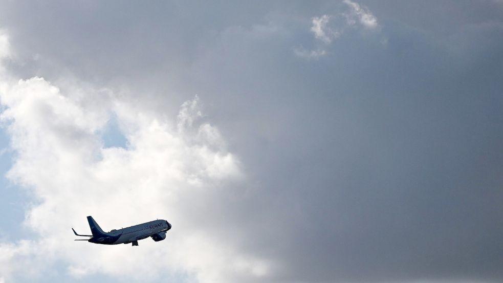 Ein Flugzeug fliegt nach seinem Sart am Flughafen München auf dunkle Wolke zu. Foto: Angelika Warmuth/dpa
