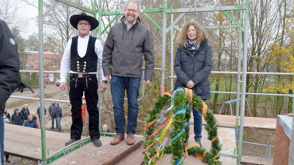 Zimmermann Rainer Diekmann (von links), Saterlands Bürgermeister Thomas Otto und Schulleiterin Monika Olling vor dem Aufhängen des Richtkranzes am neuen Anbau der Strücklinger Grundschule Marienschule. Foto: Fertig