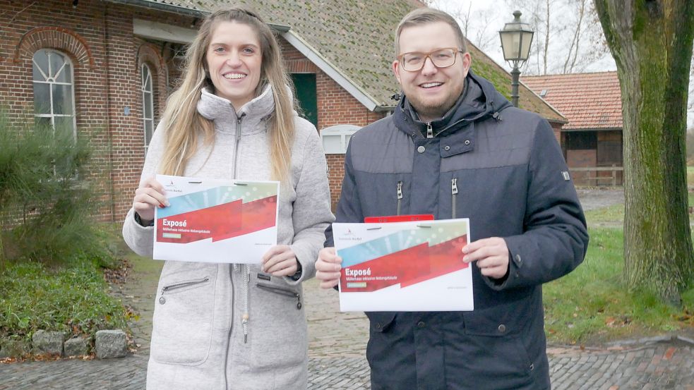 Bürgermeister Nils Anhuth und Bauamtsmitarbeiterin Maja Peters von der Gemeinde Barßel vor dem Müllerhaus, für das ein Nutzungskonzept gesucht wird. Beide halten ein Exposé in den Händen.. Foto: Kruse