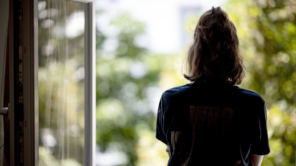 Eine Frau steht in ihrer Wohnung an einem Fenster. Die Zahl der Depressionen ist auch in Ostfriesland gestiegen. Foto: Sommer/dpa