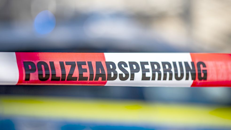 Ein Absperrband mit der Aufschrift „Polizeiabsperrung“ ist vor einem Polizeiwagen aufgespannt. Foto: David Inderlied/dpa