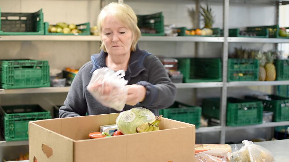 Anne Rother, Ehrenamtliche bei der Tafel Rhauderfehn, packt in einen Karton eine mögliche Zusammenstellung, die ein Kunde alle 14 Tage bekommt. Foto: Wehry