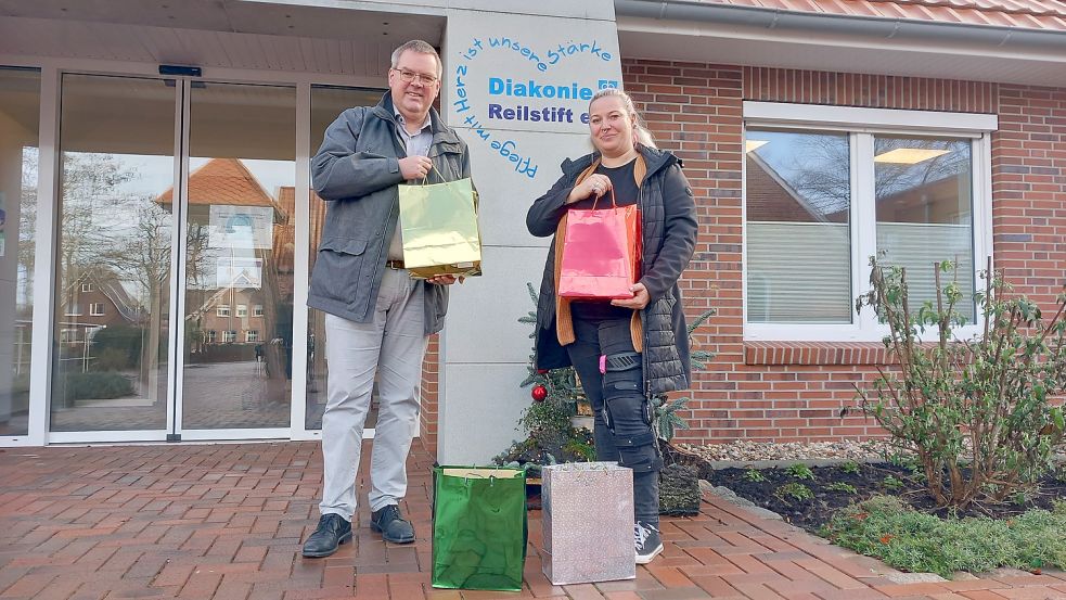 Rainer Helmers, Leiter des Reilstifts Rhauderfehn e.V.) freut sich über Taschen voller Weihnachtsgrüße von Schülerinnen und Schülern des Albrecht-Weinberg-Gymnasiums Rhauderfehn, überreicht durch Lehrerin Wiebke Rademacher.