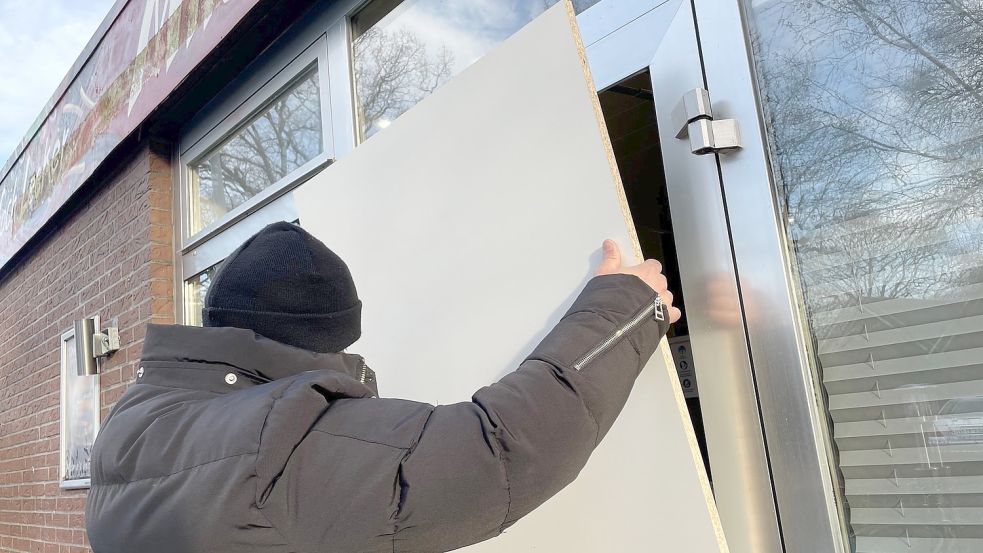 Turkan Turuku von Milanos Imbiss in Westrhauderfehn setzt eine Holzplatte als provisorische Scheibe in die Tür. In dem Laden wurde in der Nacht zu Dienstag eine Glasscheibe eingeworfen.Foto: Hellmers