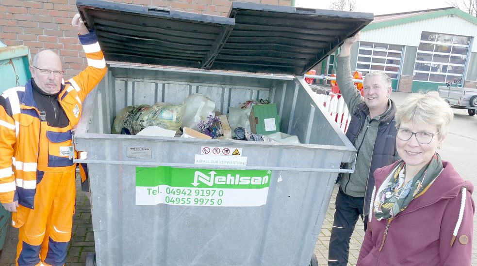 Alfred Focken (von links), Frank Kappernagel und Adelheid Bollen stehen an einem Container mit Hausmüll, der in Rhauderfehn auf dem Bauhof gesammelt wird. Focken gehört zur Müllkolonne, Kappernagel leitet den Bauhof und Sekretärin Adelheid Bollen verwaltet die Fotos der wilden Müllkippen und leitet die Anzeigen zur Polizei weiter. Foto: Wieking