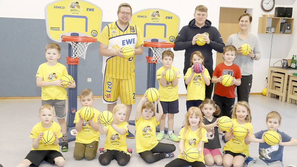 In der Kita „Die Arche“ in Elisabethfehn läuft das Projekt BASKita mit den Kindern. Mit dabei ist auch Bürgermeister Nils Anhuth (hinten, von links), Fan der EWE Baskets Oldenburg. Trainer Roman Eisner ist für das Projekt unterwegs, vor Ort wird er von Kita-Mitarbeiterin Rita Salomon unterstützt. Foto: Passmann