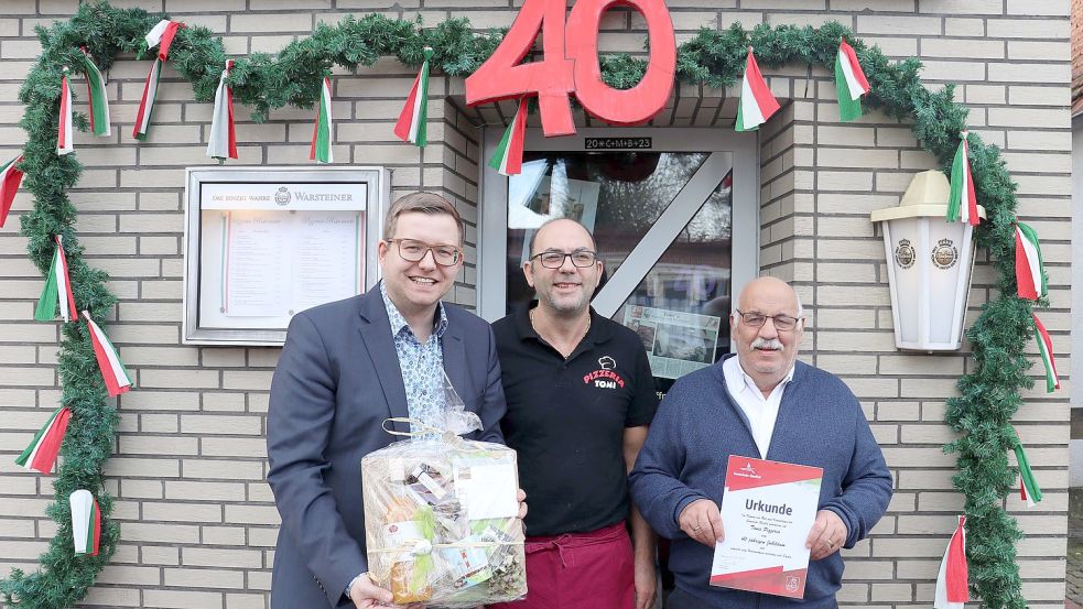 Antonio Banda (rechts) und sein Neffe und Nachfolger Sandro (Mitte) nahmen zum 40-jährigen Bestehen ihres Lokals eine Urkunde und ein Präsent von Barßels Bürgermeister Nils Anhuth entgegen. Foto: Gemeinde