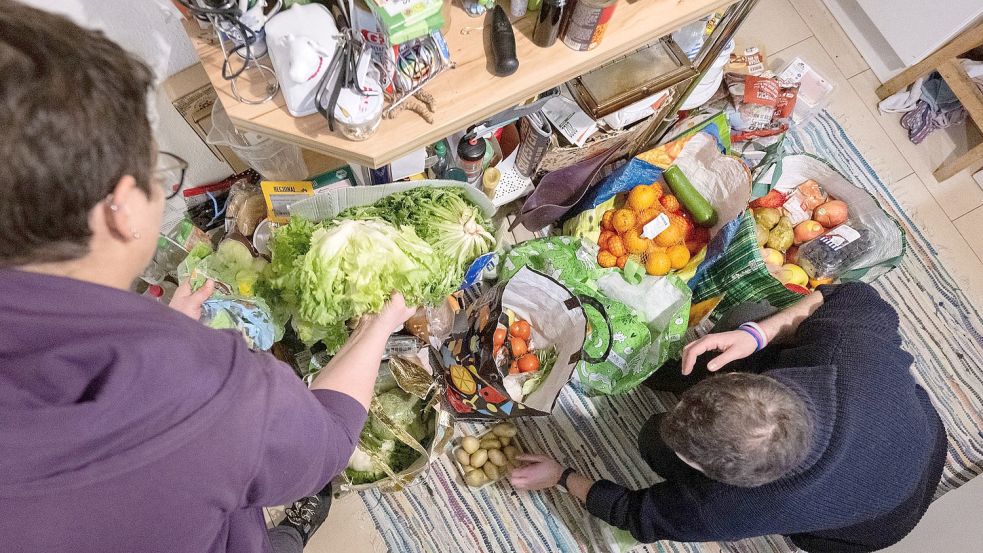 Aktivistinnen sortieren Lebensmittel, die sie zuvor aus Mülltonnen eines Supermarktes im Großraum Stuttgart geholt haben, aus ihren Taschen. Foto: Murat/DPA