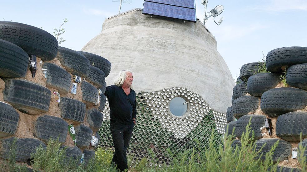 Architekt Michael Reynolds vor seinem „Erdschiff“, gedämmt mit Autoreifen und Glasflaschen. Foto: imago stock&people