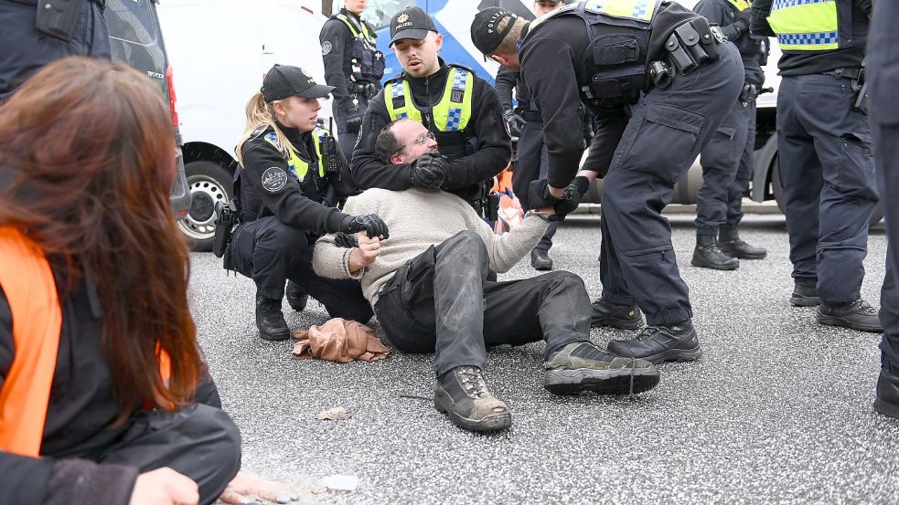 Polizisten wirken auf einen Klimaaktivisten der „Letzten Generation“ auf den Elbbrücken ein. Mitglieder der Gruppe hatten sich am vorigen Sonnabend dort festgeklebt und die wichtige Zufahrt von Süden in die Stadt über Stunden blockiert. Foto: Jonas Walzberg/dpa