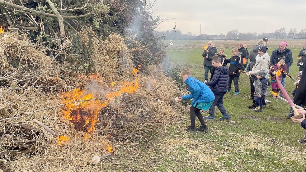 Die Kinder durften in Folmhusen ihre Fackeln auf den großen Strauchhaufen werfen und so das Osterfeuer entzünden. Foto: Janßen