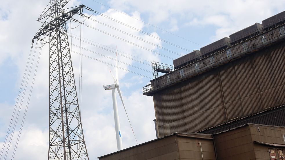 Ein Strommast und ein Windrad stehen neben dem Gelände eines Stahlwerks des Unternehmens ArcelorMittal GmbH. Ein Vorstoß aus Niedersachsen beabsichtigt, besonders energieintensive Unternehmen von hohen Strompreisen zu entlasten. Foto: Jonas Walzberg/dpa
