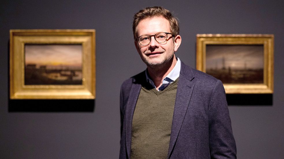 Florian Illies, Buchautor, Kunsthistoriker und Kurator, steht im Museum Kunstpalast zwischen den Werken „Küstenlandschaft im Morgenlicht“ (l, 1816/18) und „Schiffe auf der Reede“ (1818) des Künstlers Caspar David Friedrich. Foto: dpa