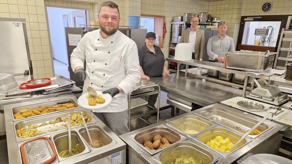 Küchenleiter Marco Löschen und Mitarbeiterin Maike Zillmer bereiten die Portionen für die Heimbewohner vor. Jens Rattke, Bereichsleiter Arbeit und Teilhabe bei der Lebenshilfe Leer, und Heimleiter Andreas Cramer freuen sich, dass sie bald auch externe Gäste bekochen. Foto: Gettkowski