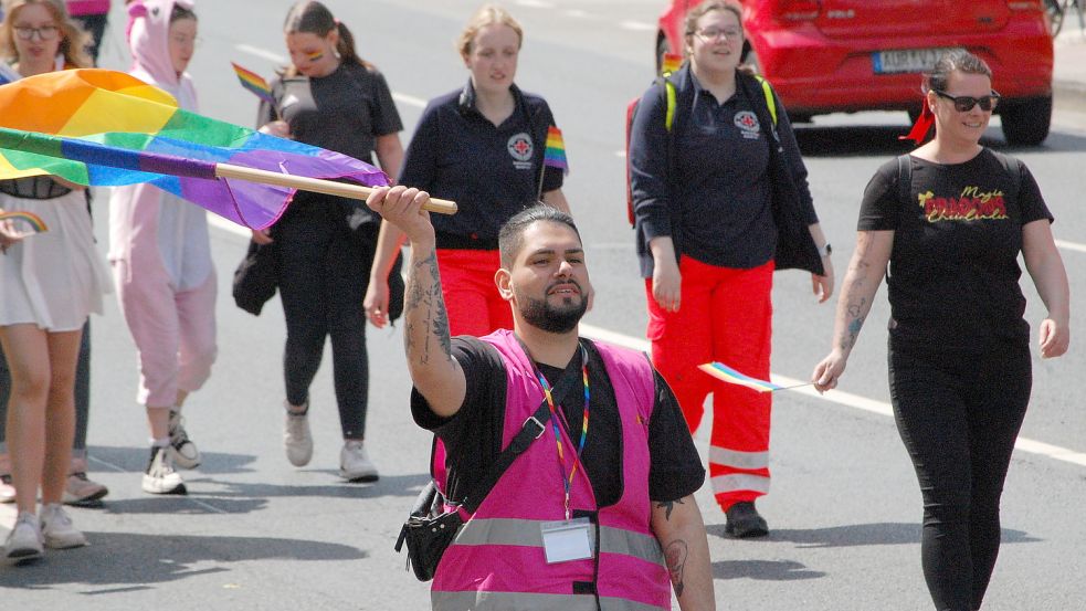Die Teilnehmer schwenken Regenbogenfahnen.