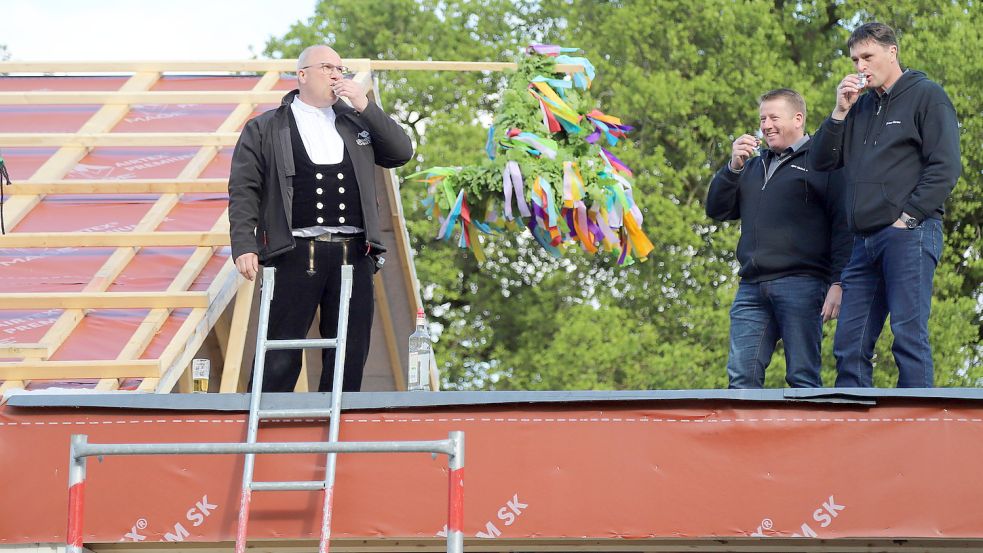 Einen Schluck auf den im Bau befindlichen Anbau der Schützenhalle nahmen (von links) Zimmermann Markus Schnitger, Schützenvereinsvorsitzender Ludger Meinders und Thomas Harms. Fotos: Passmann
