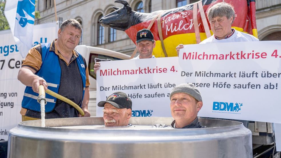 Die Krummhörner Landwirte Gerd Uken (links) und Peter Habbena haben sich in einen Milchtank gesetzt. Ihnen steht die Milch sinnbildlich „bis zum Hals“. Foto: Bundesverband Deutscher Milchviehhalter