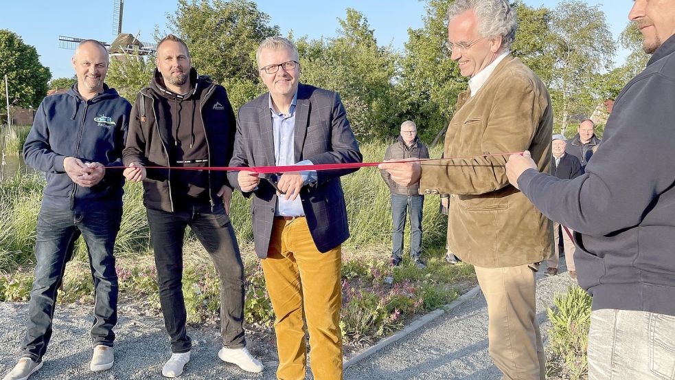 Bürgermeister Theo Douwes (Mitte) eröffnete mit einem Schnitt durchs Band den Erlebnispfad gemeinsam mit Vertretern des Dorfvereins und Rotarieren. Foto: Hinderks