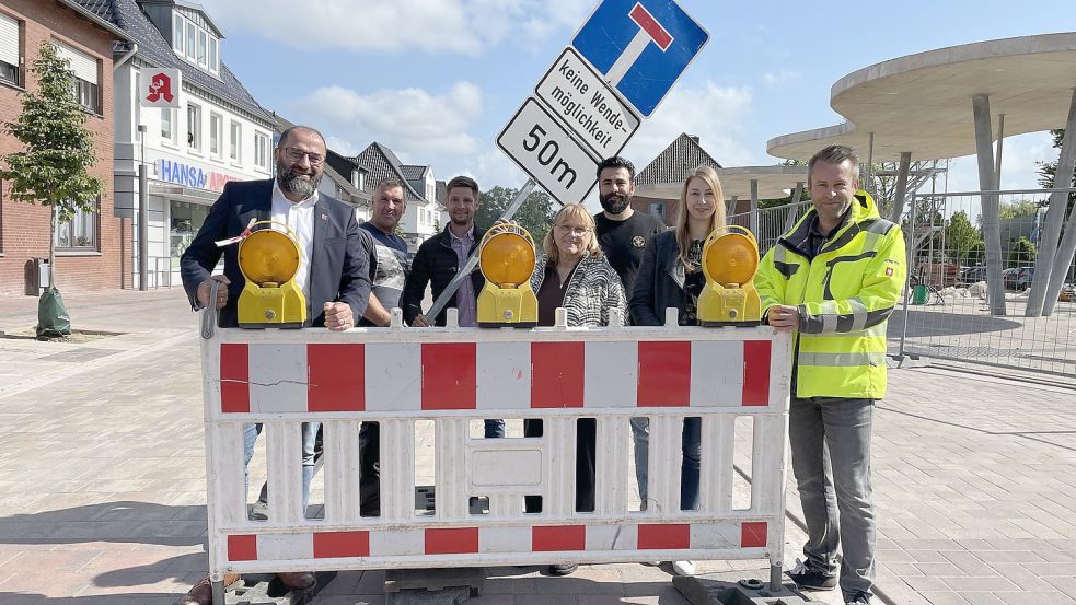 Kurz vor dem Entfernen der letzten Absperrbake nahmen an der sanierten Kirchstraße Aufstellung (von links): Friesoythes Bürgermeister Sven Stratmann, Bogdan Rorat (bauausführende Firma Abeln), Dustin Schütte, Leiter des städtischen Baubetriebshofes, Heidi Holtwessels von der Stadtbäckerei Frerker, Samet Aktas von Sam’s Babershop, Carolin Haskamp (Untere Verkehrsbehörde) sowie Matthias Neiteler vom Fachbereich Stadtentwicklung. Foto: Stadt Friesoythe