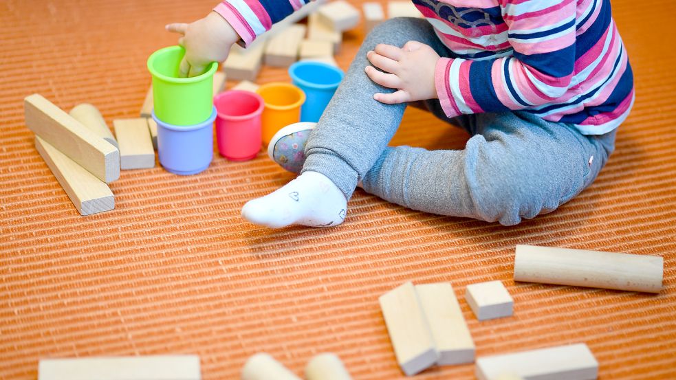 Ein Kind spielt mit Bechern und Bauklötzen. In Krippen und Kindergärten geht es jedoch um weit mehr, als nur Spielen. Dort werden Kinder gefördert und lernen Sozialkompetenzen.Foto: Uwe Anspach/dpa