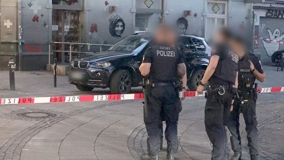 Polizisten stehen im Bremer Steintor-Viertel vor dem attackierten BMW des Ehepaars. Foto: NWM-TV
