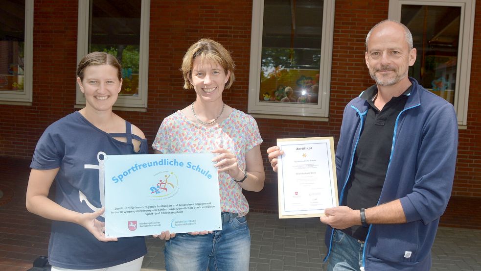 Die Grundschule Ihren darf sich ab sofort "Sportfreundliche Schule" nennen. Das entsprechende Schild und die Urkunde sowie einen Scheck überreichte Ralf Koch (Fachberater Sport vom regionalen Landesamt für Schule und Bildung, rechts) an Schulleiterin Silke Abbes (Mitte) und Sportlehrerin Katja Sinning. Foto: Weers