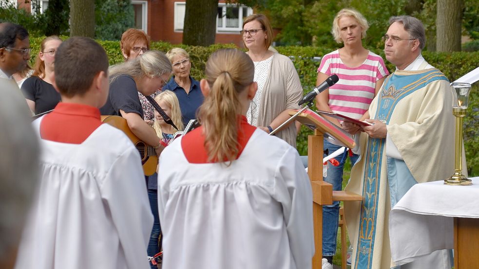 Pfarrer Torsten Brettmann (rechts) begrüßte zum Hochfest anlässlich der offiziellen Einweihung der Marien-Grotte im Pfarrgarten der katholischen Kirchengemeinde St. Bernhard Flachsmeer auch den Chor. Mit dem Lied „Unser Leben sei ein Fest“ wurde das Fest eröffnet. Foto: Ammermann