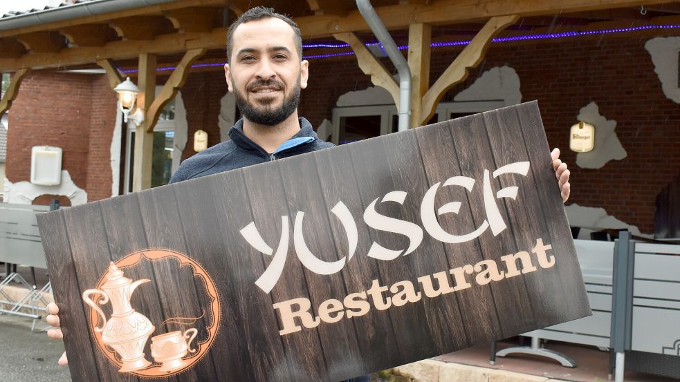 Omar Almatar hält ein Schild mit der Beschriftung des neuen Restaurants Yusef in die Luft. Er hilft zurzeit seinem Bruder und Inhaber Khaled Almatar bei den Vorbereitungen für die Eröffnung. Foto: Zein