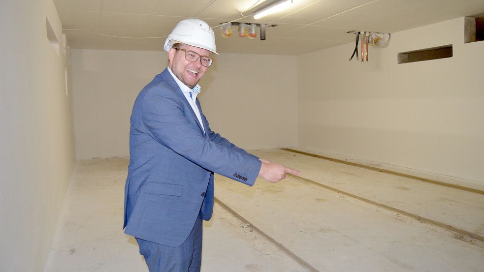 Vergnügt weist Barßels Bürgermeister auf die Fläche, wo künftig das Hochregallager für das Archiv der Gemeindeverwaltung untergebracht sein wird. Foto: Fertig