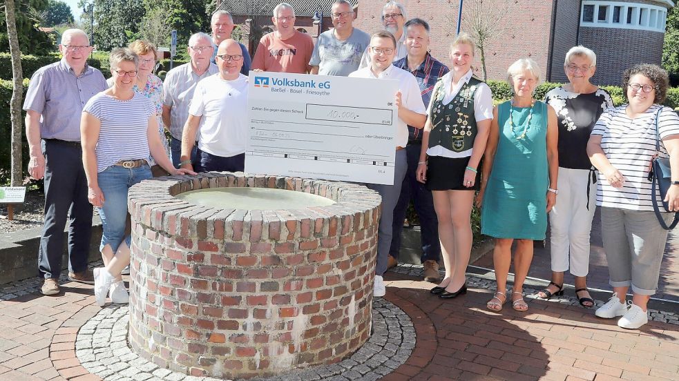 Barßels Bürgermeister Nils Anhuth (6. von rechts) hält den Scheck über 10000 Euro in Händen, den der Veranstalter des Flohmarktes Claas Meyer (5.von links ) an das Flohmarktgremium überreicht hat. Foto: Passmann