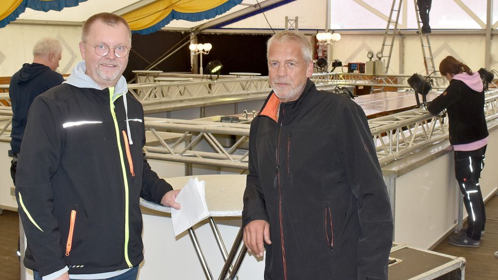 Wolfgang Harms (links) und Gerhard Tebben vom zwölfköpfigen Planungsteam mussten am Freitag noch die letzten Dinge organisieren. Im Hintergrund bauten die Mitarbeiter des Zeltverleihs Nemeyer aus Osterscheps die große Theke auf. Fotos: Zein