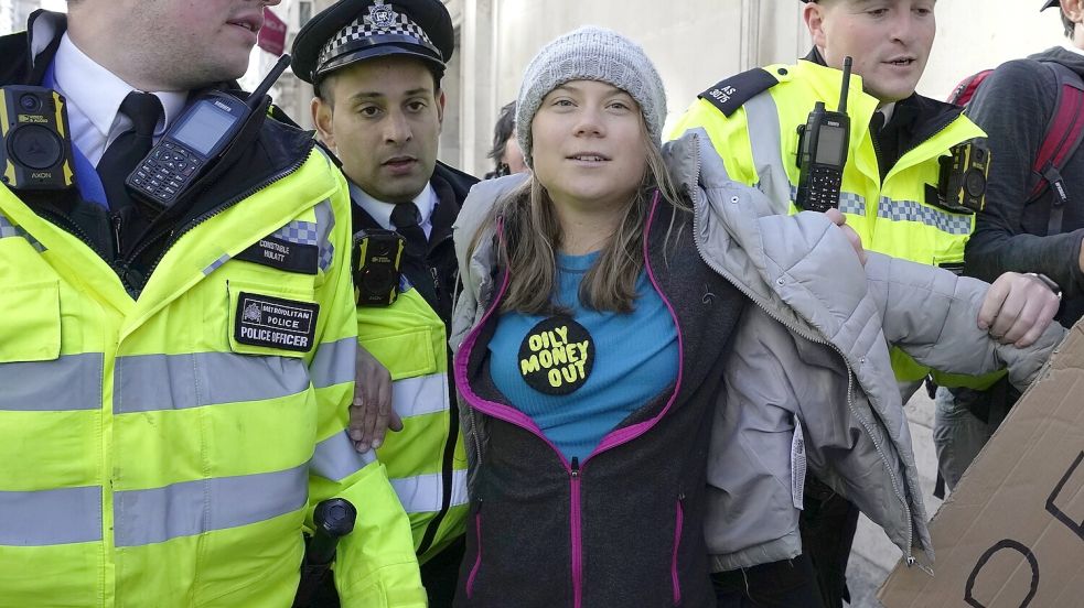 Greta Thunberg (Mitte), Klimaaktivistin aus Schweden, wird von Polizeibeamten während der „Oily Money Out“-Demonstration vor dem Intercontinental Hotel abgeführt. Foto: dpa/AP/Kin Cheung