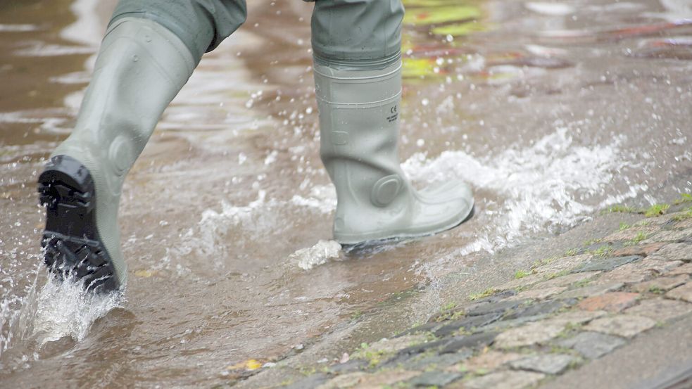 Flensburg, Schleswig-Holstein, Aufräumarbeiten nach Jahrhundert-Hochwasser in Flensburg am Hafen (West). Mit Gummistiefe Foto: IMAGO/Willi Schewski
