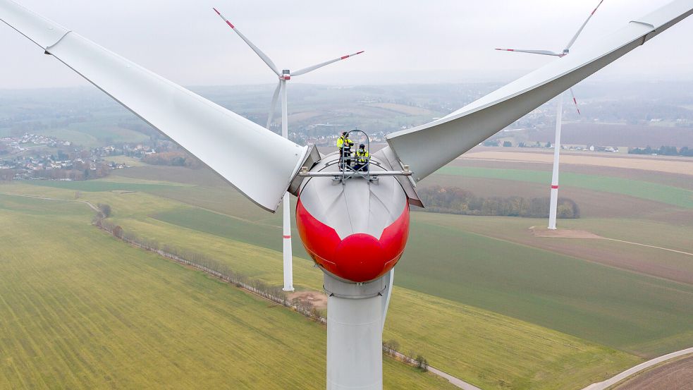 Zwei Techniker warten eine Windkraftanlage vom Typ Enercon E92 (Luftaufnahme mit Drohne). Foto: Woitas/dpa/Archiv
