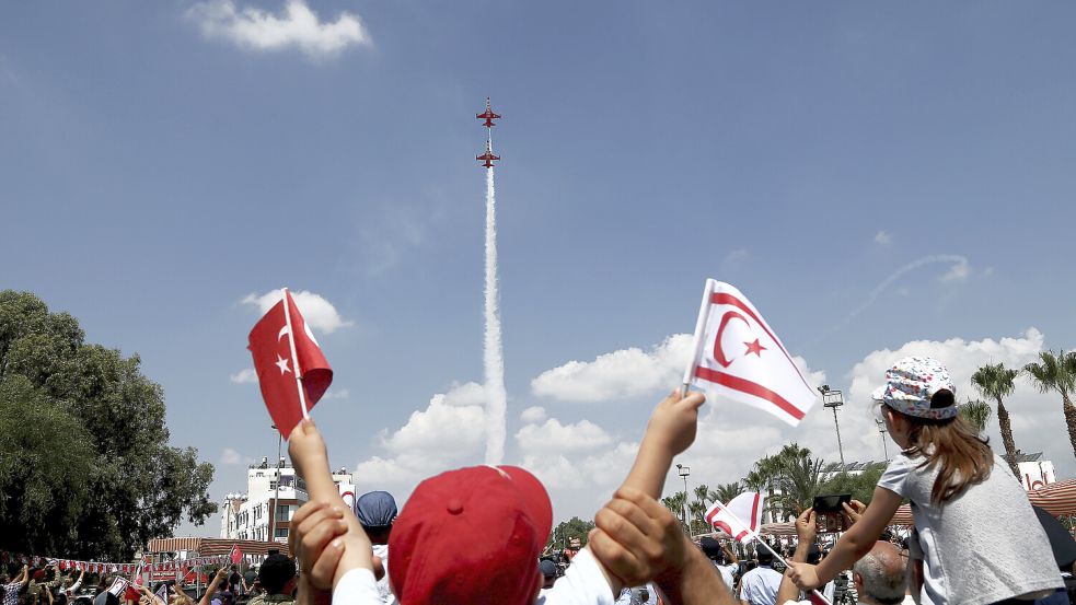 Auf einer Militärparade hält ein Kind eine türkische Flagge und eine der Türkischen Republik Nordzypern hoch. Die Türkei ist weltweit der einzige Staat, der die Nordhälfte der Insel Zypern anerkennt. Foto: dpa/Petros Karadjias