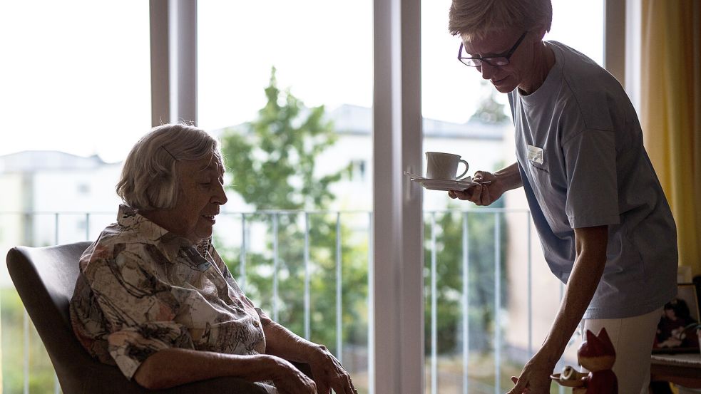 Eine Pflegekraft kümmert sich in einem Pflegeheim um eine ältere Dame und bringt ihr Kaffee und Kuchen. Foto: dpa/Christoph Schmidt