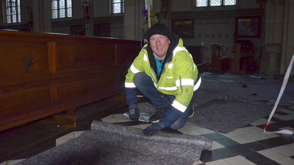 Elmar Schickling rollt in der Kirche St. Jakobus den Bodenbelag zusammen, der die Fliesen im Kirchenschiff vor der Belastung durch die Arbeitsbühne geschützt hat, die sein Unternehmen für die Ausführung der Reparatur gestellt hat. Foto: Fertig
