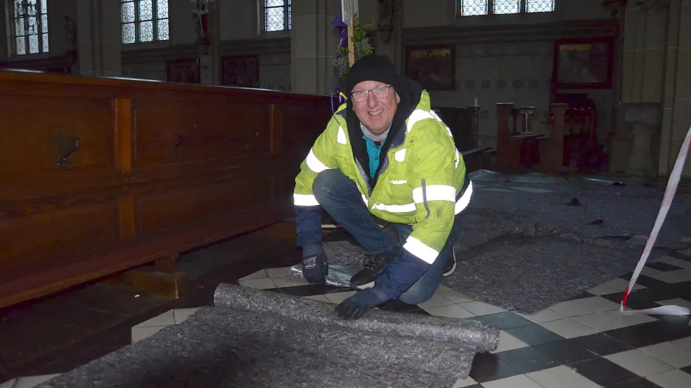 Elmar Schickling rollt in der Kirche St. Jakobus den Bodenbelag zusammen, der die Fliesen im Kirchenschiff vor der Belastung durch die Arbeitsbühne geschützt hat, die sein Unternehmen für die Ausführung der Reparatur gestellt hat. Foto: Fertig