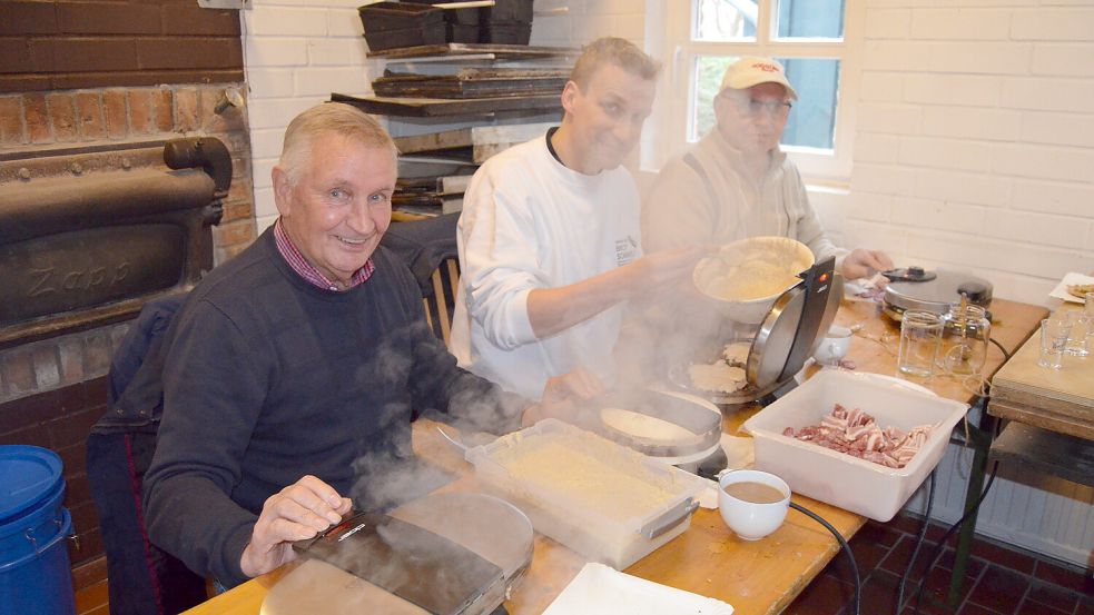 Johann Meinders (von links), Volker Garrels und Heinz-Bernd van Osten im Backhaus der Rhauder Mühle vor den Waffeleisen, um Speckendicken zu backen. Das Rezept stammt von Meinders‘ Mutter Gerhardine, die es einst aus dem Rheiderland mitbrachte. Foto: Fertig