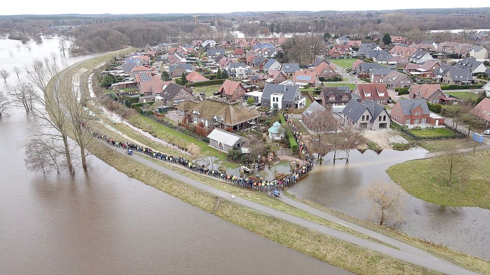 Haren an der Ems: Einsatzkräfte und Einwohner sichern mit einer Menschenkette gemeinsam einen durchweichten Deich im Landkreis Emsland. Nach Beschädigungen an einem Deich in der Nacht zu Sonntag waren Feuerwehrleute ausgerückt, um ihn zu sichern. Wegen des Hochwassers in weiten Teilen Niedersachsens hat es bereits an mehreren Stellen Beschädigungen an Deichen gegeben. Foto: Albrecht / DPA