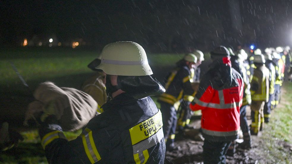 Mit einer Menschenkette werden gefüllte Sandsäcke zu Deich-Bruchstellen in Ostfriesland gebracht. Foto: picture alliance/dpa/Lars Penning